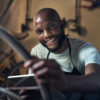 Portrait of a young man holding a digital tablet working at a bicycle repair shop.